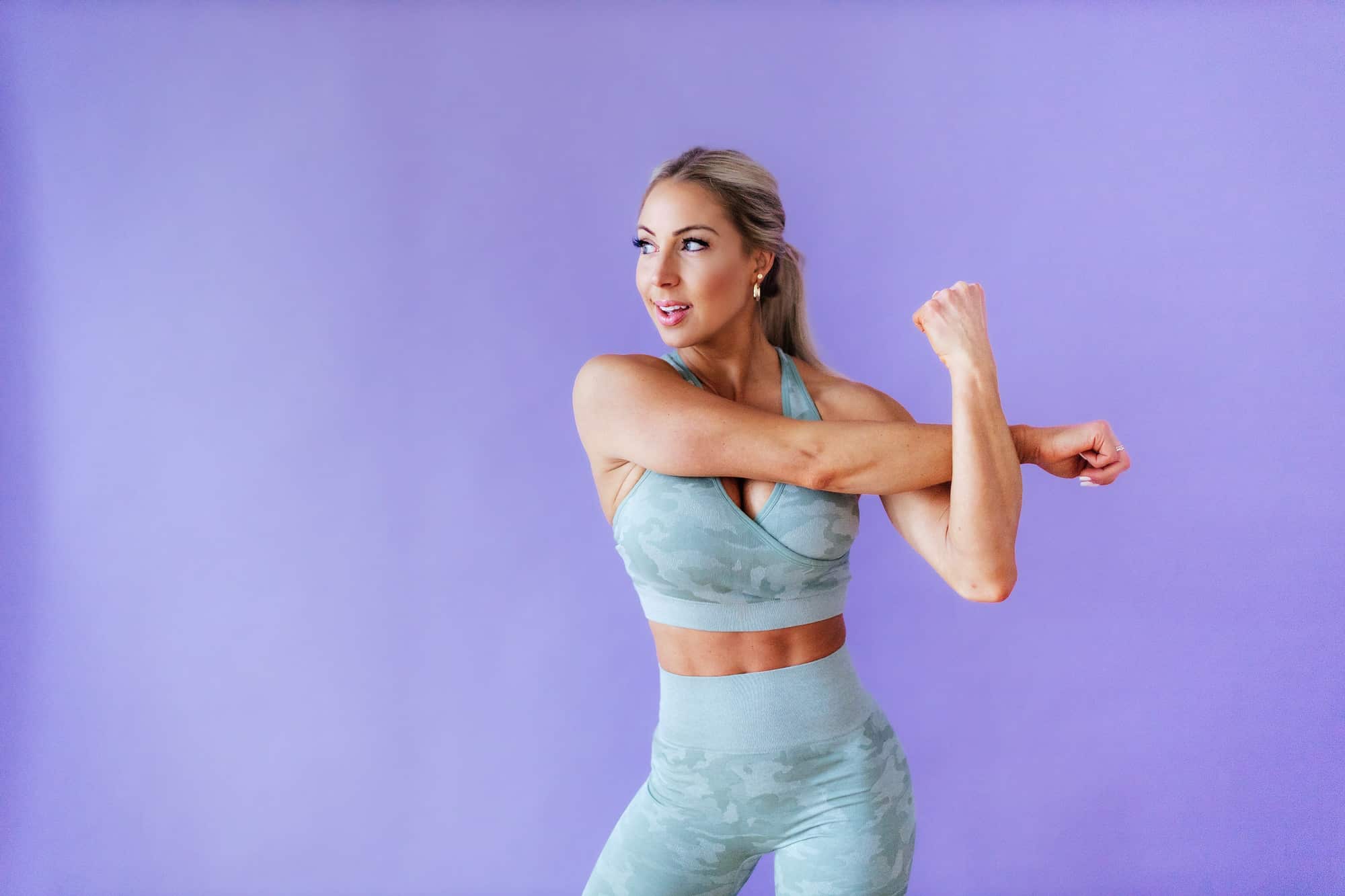 Coach Taylor stretching her upperarm and looking to the side